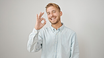 Young caucasian man smiling with ok gesture over isolated white background