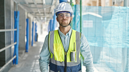 Young caucasian man architect standing with serious expression at construction place