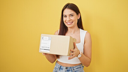 Young beautiful hispanic woman smiling confident holding package over isolated yellow background