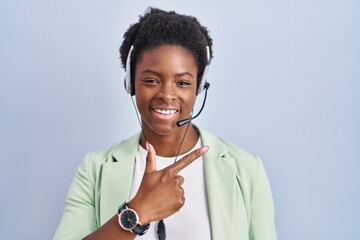 African american woman wearing call center agent headset cheerful with a smile on face pointing...