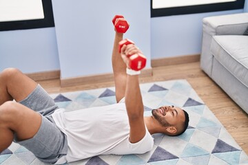African american man using dumbbells training push up at home