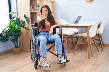 Fototapeta premium Young teenager girl sitting on wheelchair at the living room with open hand doing stop sign with serious and confident expression, defense gesture