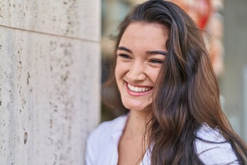 Young hispanic woman smiling confident looking to the side at street