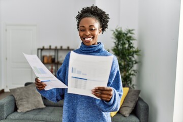 African american woman reading document standing at home