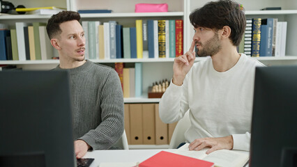 Two men students using computer studying at library university