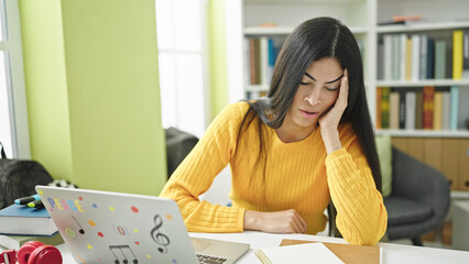 Young beautiful hispanic woman student tired studying at library university