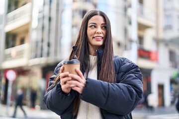 Young beautiful hispanic woman smiling confident drinking coffee at street