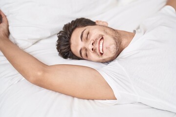 Fototapeta na wymiar Young hispanic man smiling confident lying on bed at bedroom