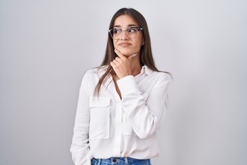 Young brunette woman wearing glasses thinking worried about a question, concerned and nervous with hand on chin
