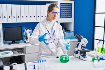 Fototapeta premium Young woman scientist measuring liquid at laboratory