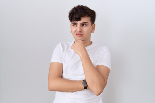 Young non binary man wearing casual white t shirt thinking worried about a question, concerned and nervous with hand on chin