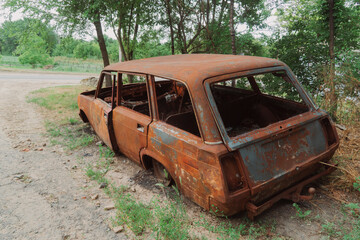 Countryside. On the side of the road is a destroyed, burned-out civilian car. War in Ukraine