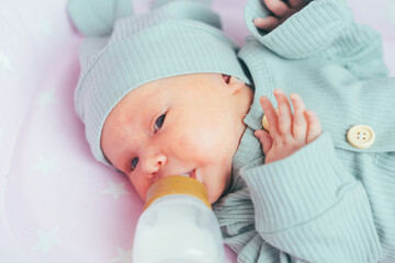 Mom feeds a newborn baby with a bottle at home