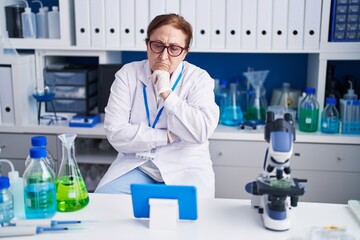 Fototapeta premium Senior woman scientist using touchpad with serious expression at laboratory