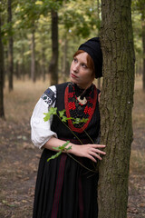А woman in Ukrainian national embroidered dress vyshyvanka, outdoors in the forest. - 619778062