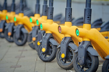 Electric scooters for rent stand on parking zone, one scooter discharged. Electric scooters parked...