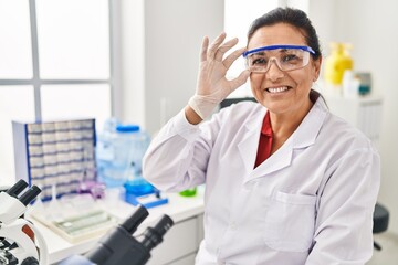 Middle age hispanic woman wearing scientist uniform working at laboratory