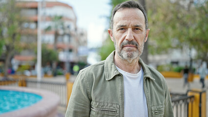 Middle age man standing with serious expression at park