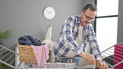 Middle age man hanging clothes on clothesline at laundry room