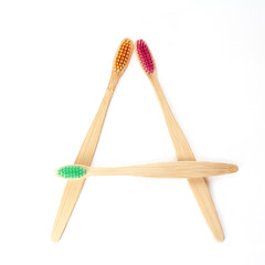 Three multicolored bamboo toothbrushes isolated on a white background. square frame layout. Oral hygiene. Recyclable raw materials