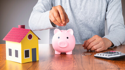 Saving money for buy home or investments. Home model and piggy bank  on table.