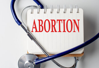 ABORTION word on notebook with medical equipment on background