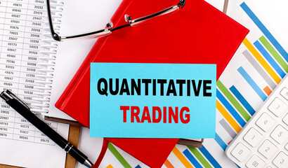 QUANTITATIVE TRADING text on a sticky on red notebook on chart background