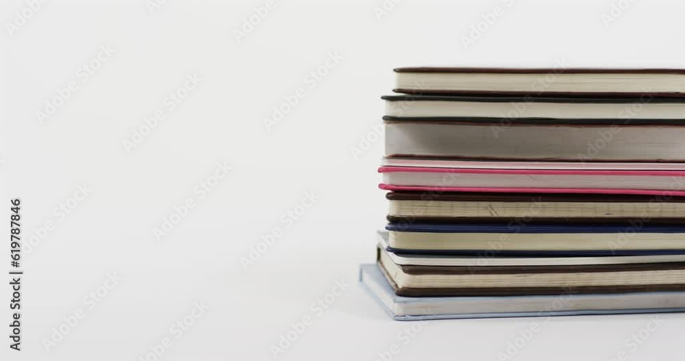 Poster Close up of stack of books on white background, in slow motion