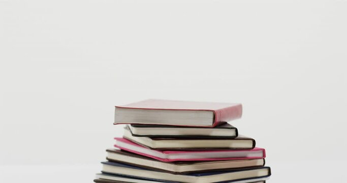 Close up of stack of books on white background, in slow motion