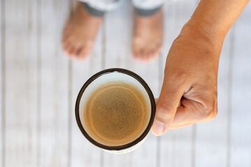 Fototapeta na wymiar taza de café con espuma en manos de una mujer, vista cenital