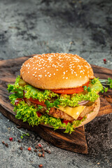 home made tasty burger cheese slice, tomato, onion,lettuce, mayonnaise, white bun, Fat unhealthy food. vertical image. top view. place for text