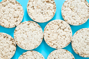 Puffed rice cakes on blue background, flat lay.