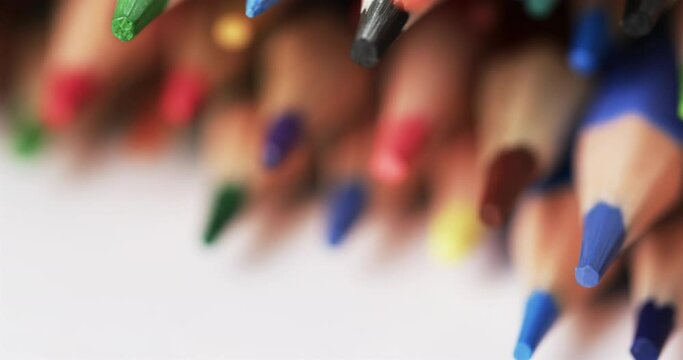 Close up of colourful pencil crayons on white background, in slow motion