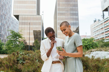 Diverse Businesswomen Laughing with Smartphone in Park