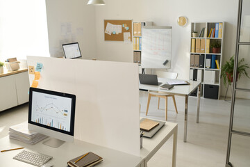 Modern office with computers with graphs on monitors on workplaces of business people
