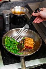 man chef cooking fried tuna fish and green bean in frying pan on kitchen