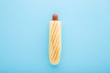 Fresh french hot dog with red ketchup on light blue table background. Pastel color. Closeup. Fast...
