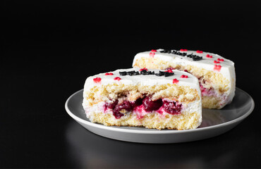 Sliced bento cake with cherry filling on a gray plate on a black background