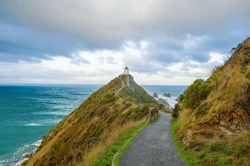 Nugget Point Lighthouse in Ahuriri Flat, New Zealand on a cloudy afternoon.