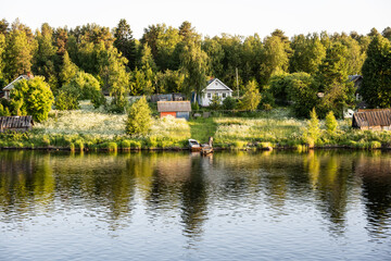 Fototapeta na wymiar landscape with a river, a forest and buildings on the shore on a bright summer day