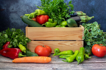 Various vegetables on a wooden table. Tomato, Green Pepper, Red Pepper, Parsley, Carrot, Eggplant, Cucumber.