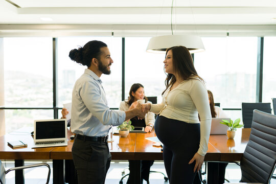 Two businesspeople shaking hands during a meeting in office board room