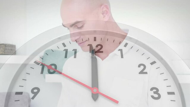 Animation of clock ticking over caucasian businessman using tablet