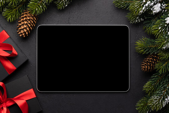 Tablet with blank screen, gift boxes and Christmas decor