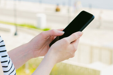 Close-up of a smartphone in female hands. Woman at the street surf the internet