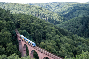 old arch Bridge railway viaduct between hills in the green Forest Germany trees