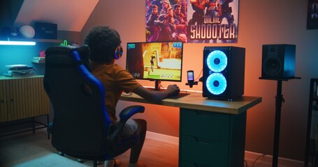 African American young gamer in headphones plays online third-person 3D shooter on modern PC in stylish neon room. Video game live streaming or cybersport competition. Gaming at home. © Framestock