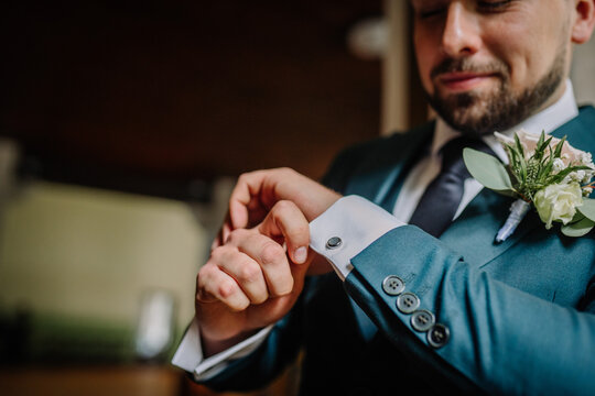 Man wearing suite, adjusting cufflink, mid section, close-up