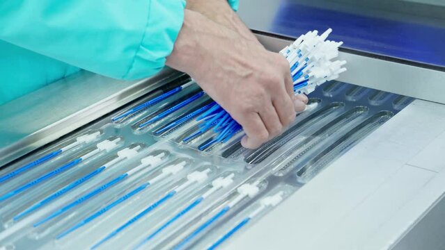 Factory workers assembling products. Production of cytobrushes, probes. Conveyor belt of factory line. Manufacturing line. Packaging. Medical equipment. Close-up in 4K, UHD