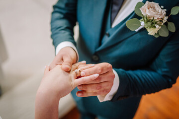Close-up of bride and groom putting ring on finger in ceremony